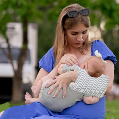 coussin allaitement maman assis dans parc bébé fille dans bras