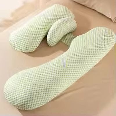 coussin de grossesse vert seul sur un lit