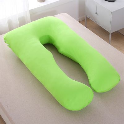 coussin grossesse vert posé sur un lit