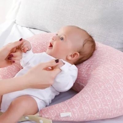 coussin allaitement bébé dos et sourit tient les doigts maman
