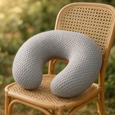 coussin d'allaitement gris sur chaise en osier